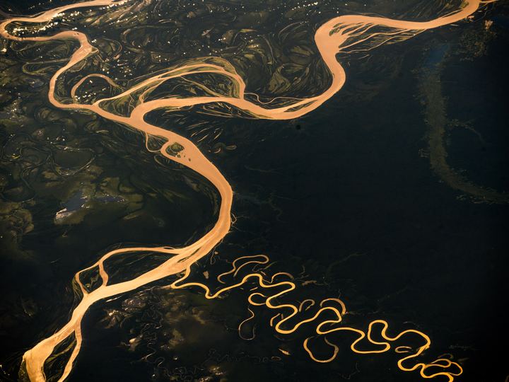 Aerial view of the wide brown Amazon River curving through green rainforest