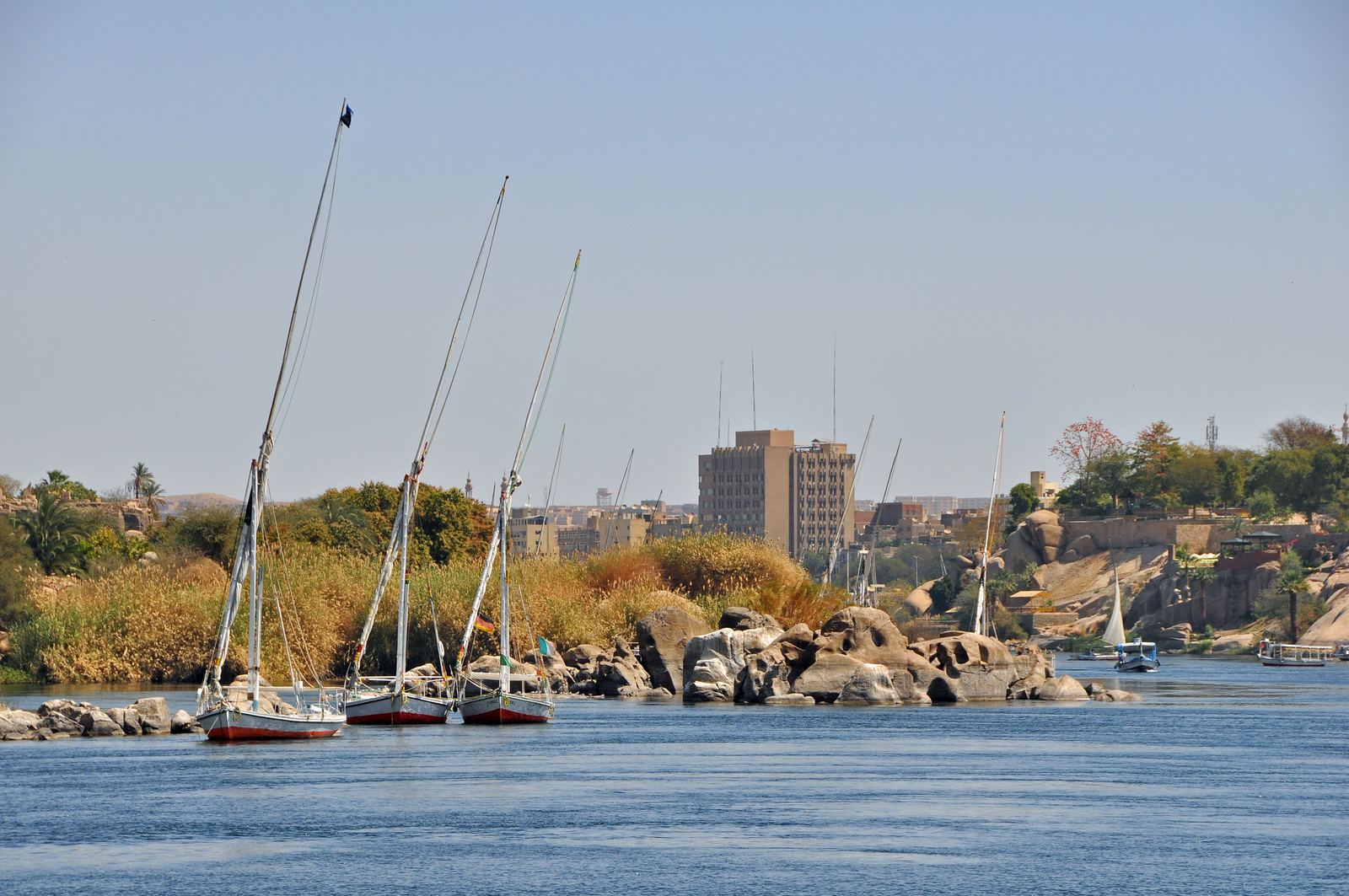Feluccas with white sails on the Nile at Aswan with desert hills behind