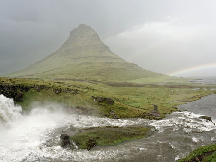 The cone-shaped Kirkjufell mountain rising above a green coastal plain in west Iceland