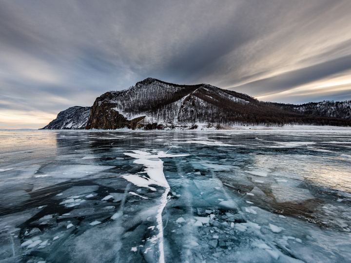 Clear blue ice and snow-dusted shore of Lake Baikal in winter